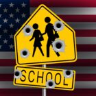 Mass shootings: American flag in background with centered yellow and black school crossing sign with 7 bullet holes.